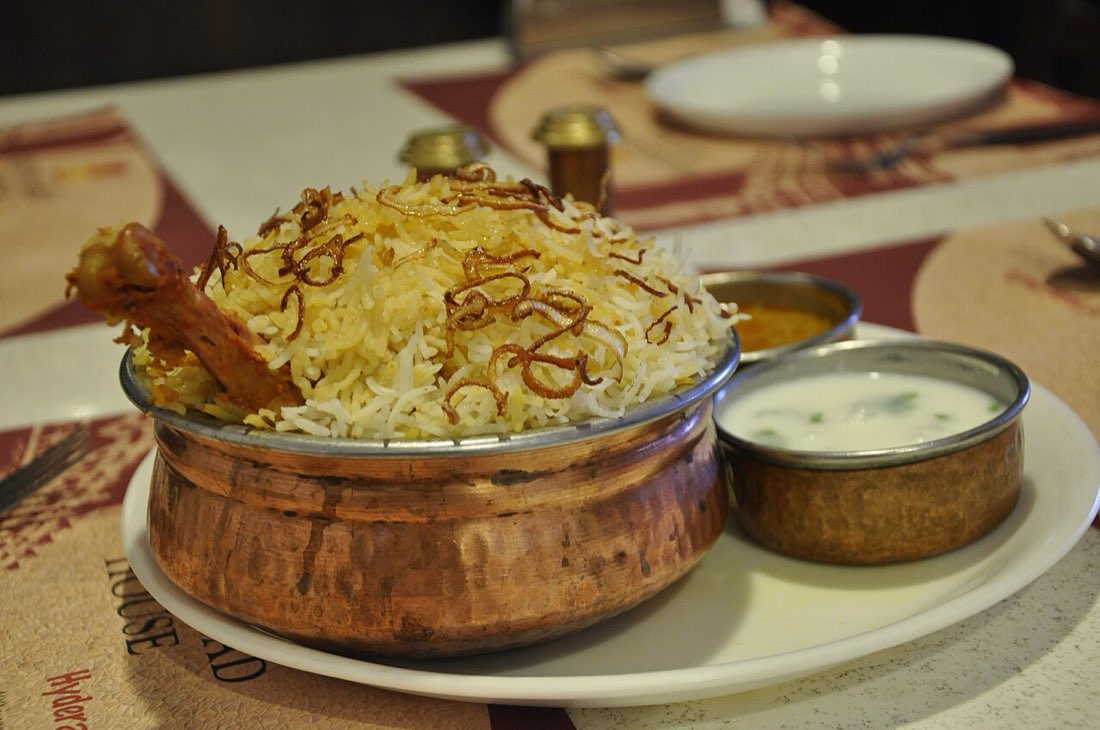 Hyderabadi biryani served with raita and curry