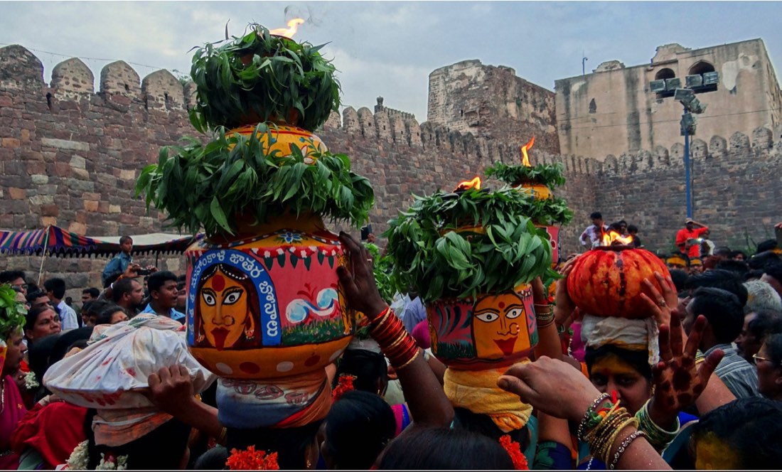 Decorated Bonalu bonam pots painted with the goddess and topped with neem leaves, carried at Golconda Fort, Hyderabad